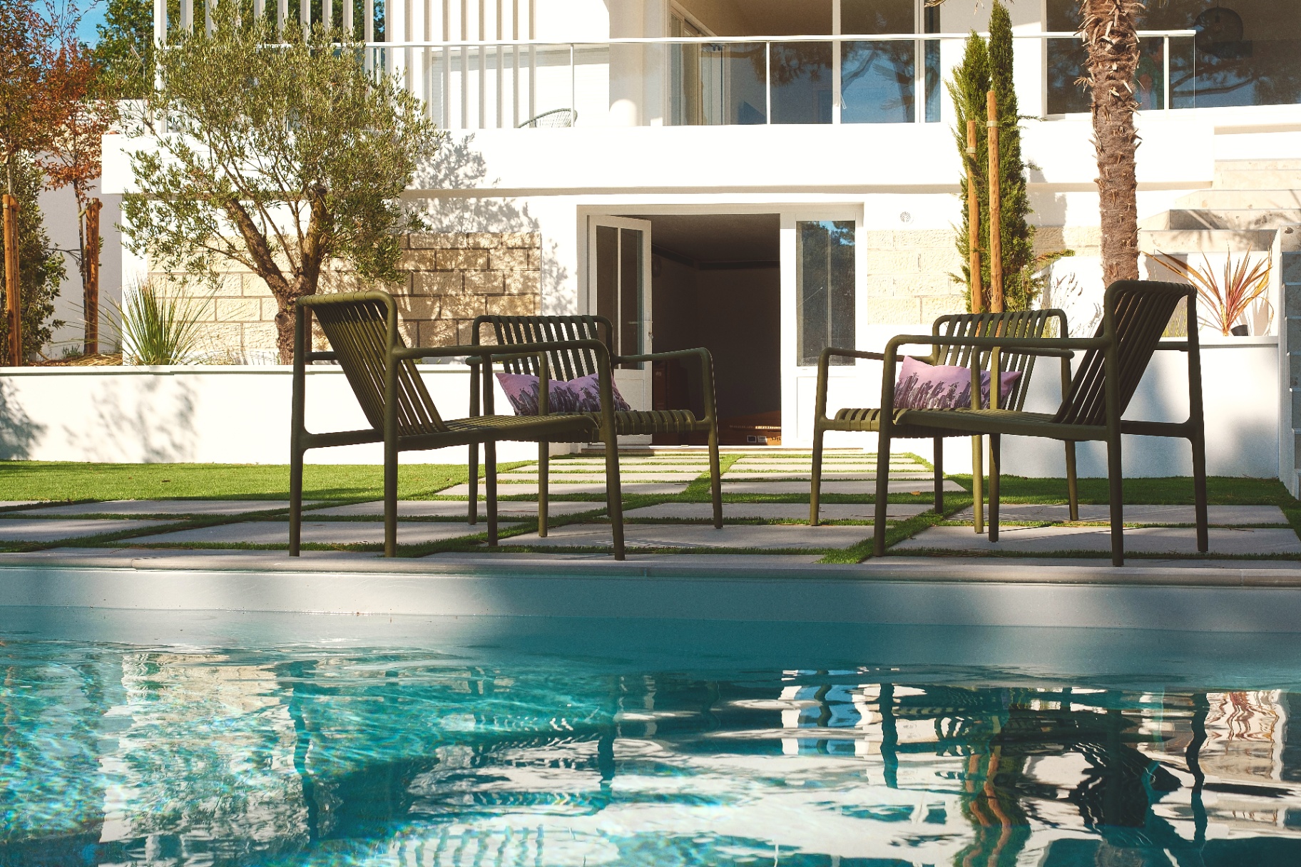 Fauteuils au bord de la piscine face à la villa